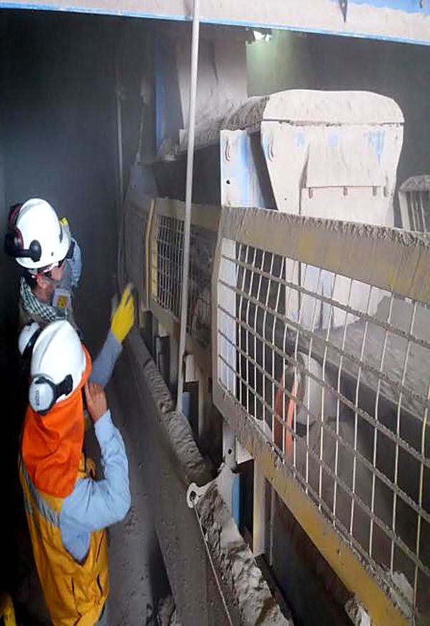 Técnicos con casco y protección auditiva revisando una correa transportadora