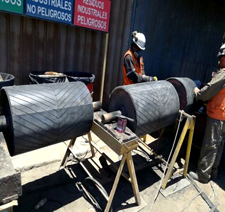 Técnicos revistiendo tambores de correa transportadora con caucho de dibujo en espiga