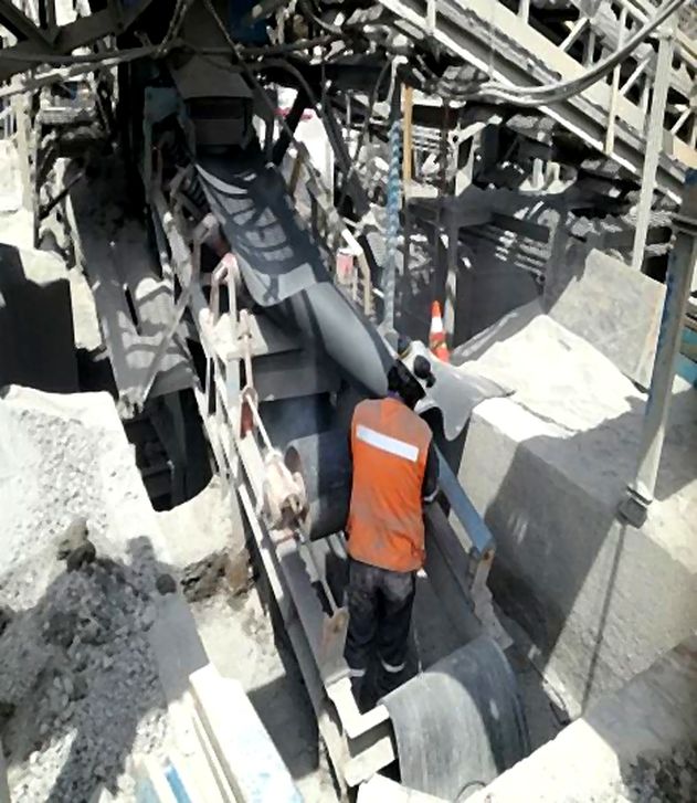 Trabajador interviniendo una correa transportadora en un punto de traspaso de planta
